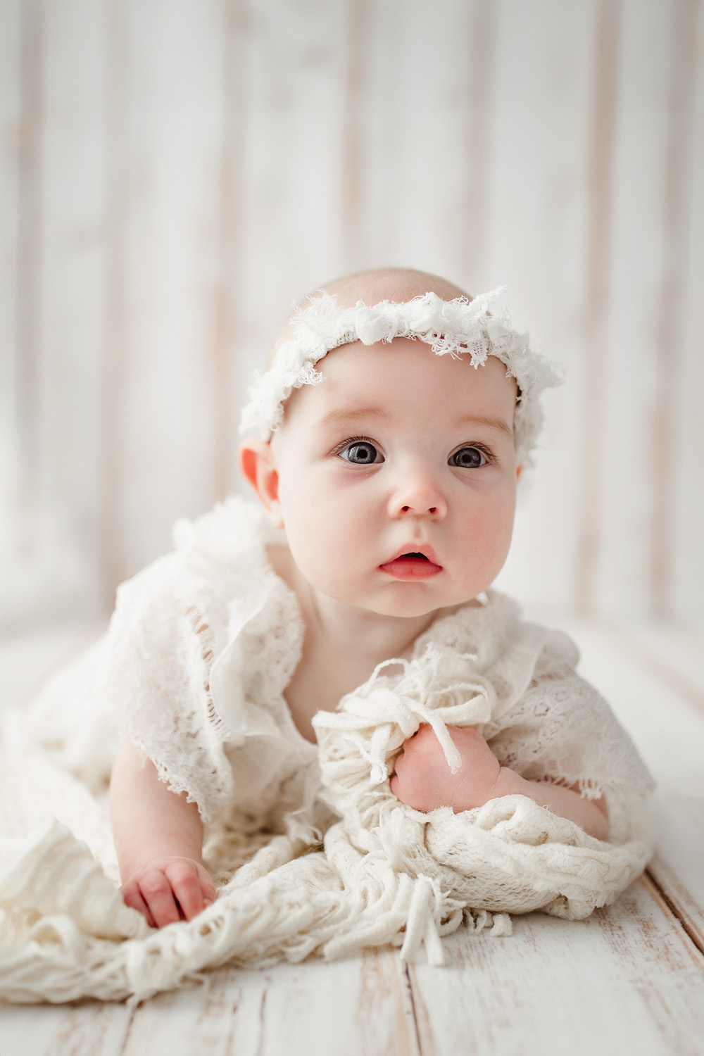 baby-girl-tummy-time-on-white-wood-plank-in-greensboro-photographer-studio-photoshoot