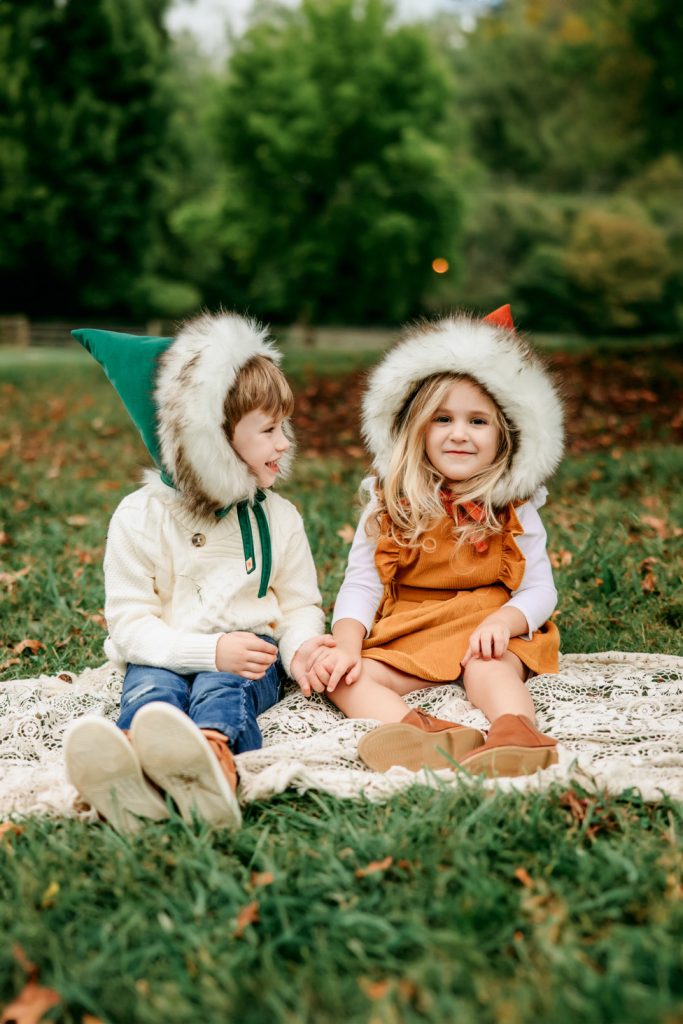 boy and girl in cute gnome hats sitting on the grass during Tanglewood park family photo session