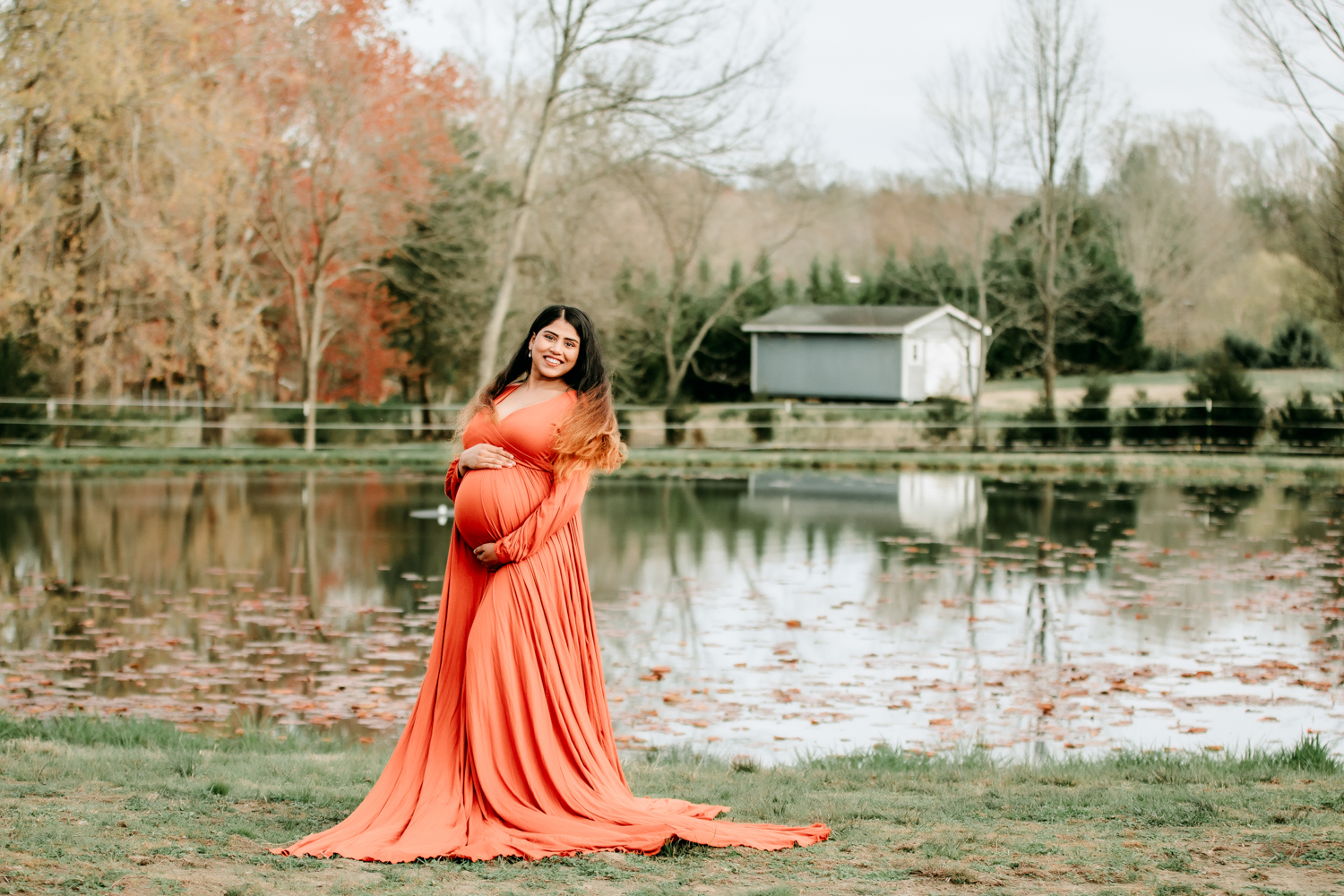 pregnant mama in orange dress by the pond at Dewberry farm Kernersville NC maternity photography session