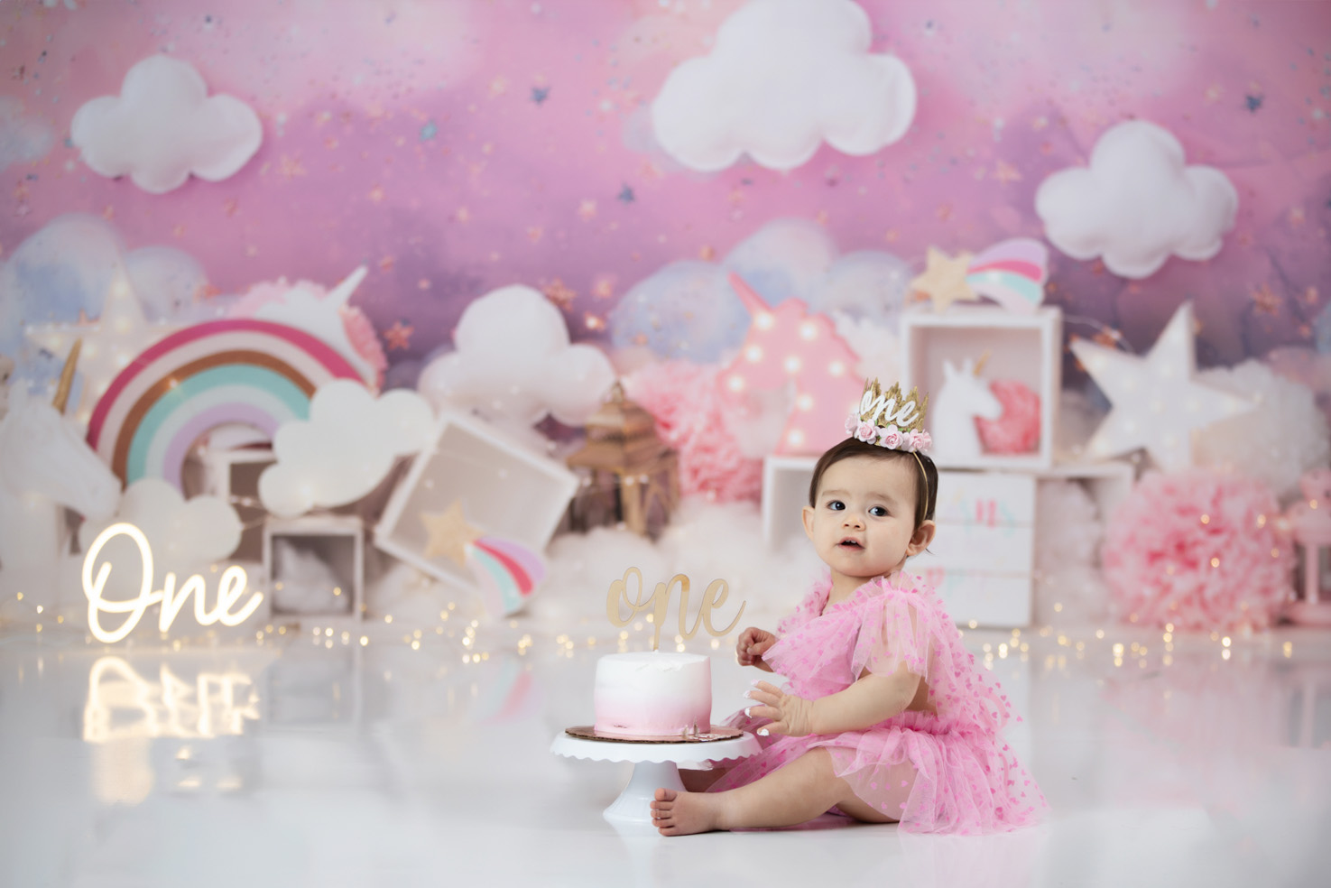 cute-baby-girl-in-pink-dress-during-cake-smash-photo-session-unicorn-theme-greensboro-photogragraphy-studio
