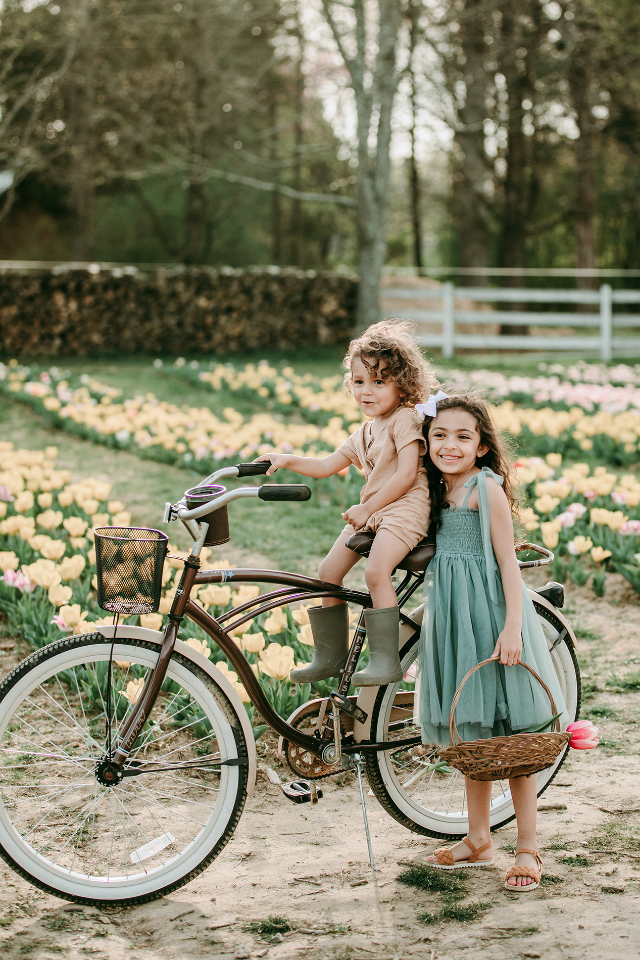 baby-boy-on-the-bike-with-big-sister-in-the-tulips-field-dewberry-farm-kernersville-NC-Charlotte-family-photographer