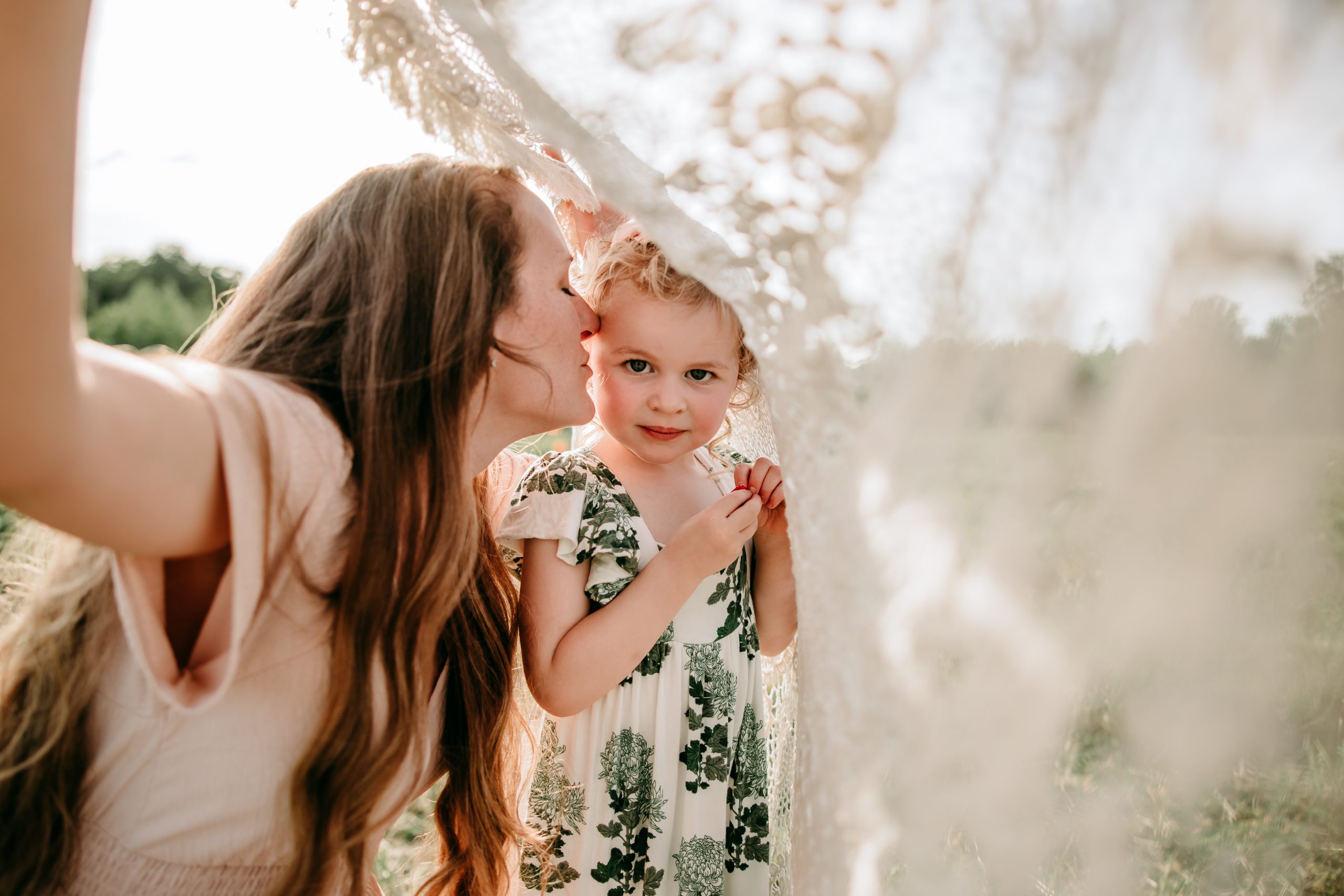 mommy-kissing-daughter-under-crotchet-blanket-during-family-photo-session-Dogwood-farms-North-carolina-Greensboro-family-photographer