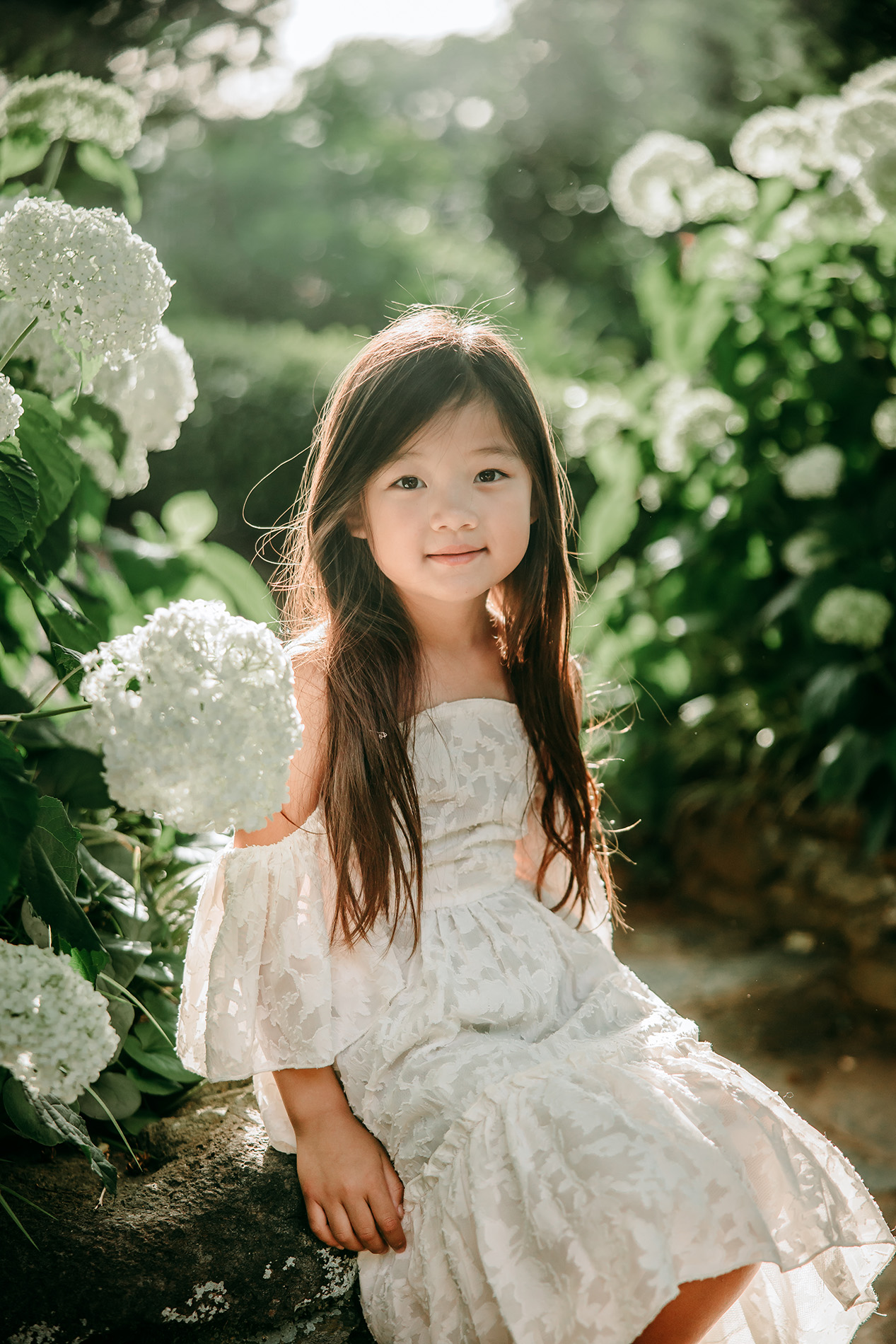pretty-little-girl-in-white-dress-sitting-next-to-flowers-during-family-photo-session-Tanglewood-botanical-garden-Greensboro-family-photographer