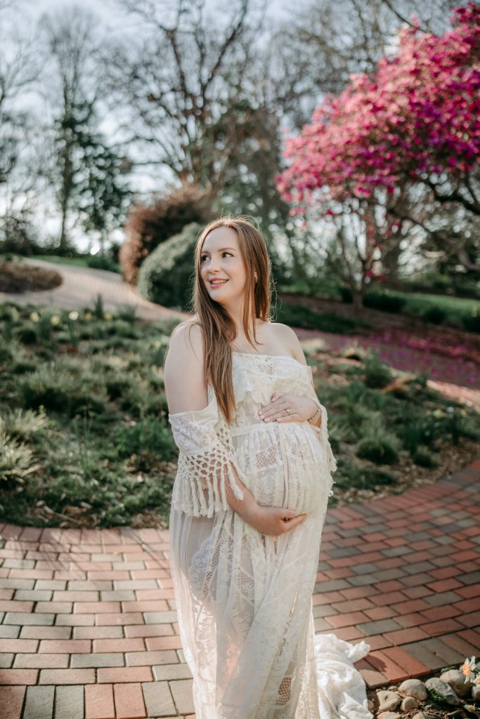 maternity mother in white lace dress during golden hour maternity session in tanglewood park arboretum winston salem NC