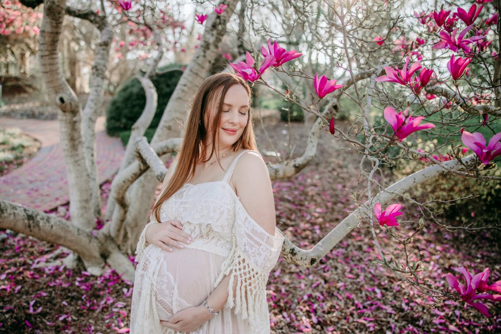 maternity mother in white lace dress under magnolia blooms in tanglewood park arboretum winston salem NC
