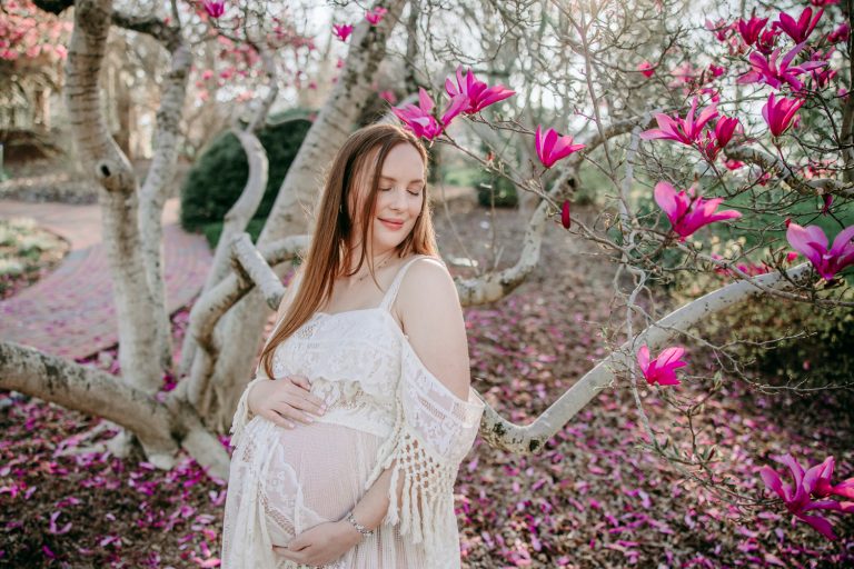 maternity mother in white lace dress under magnolia blooms in tanglewood park arboretum winston salem NC