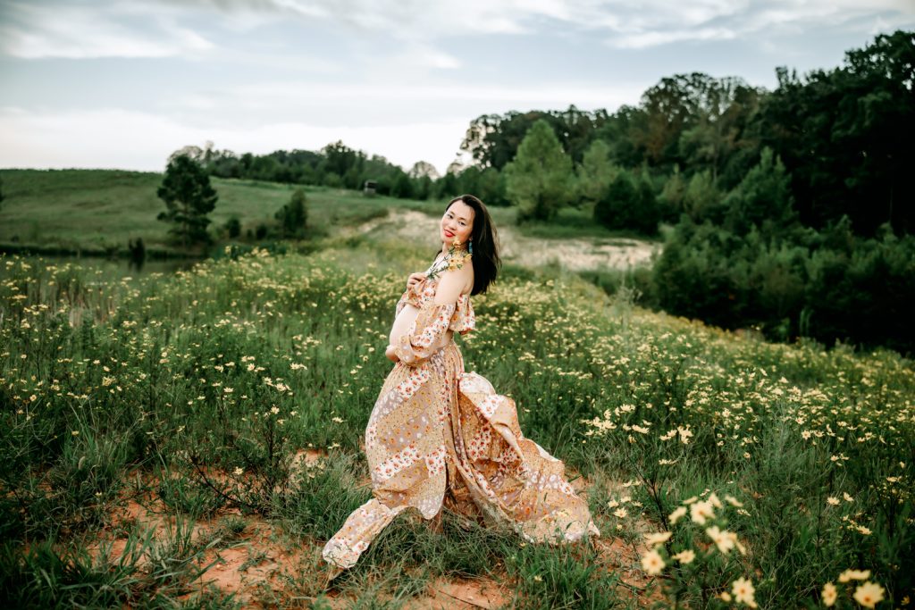 maternity mother in floral silk dress in the wild flower field during maternity photoshoot at dogwood farms North Carolina