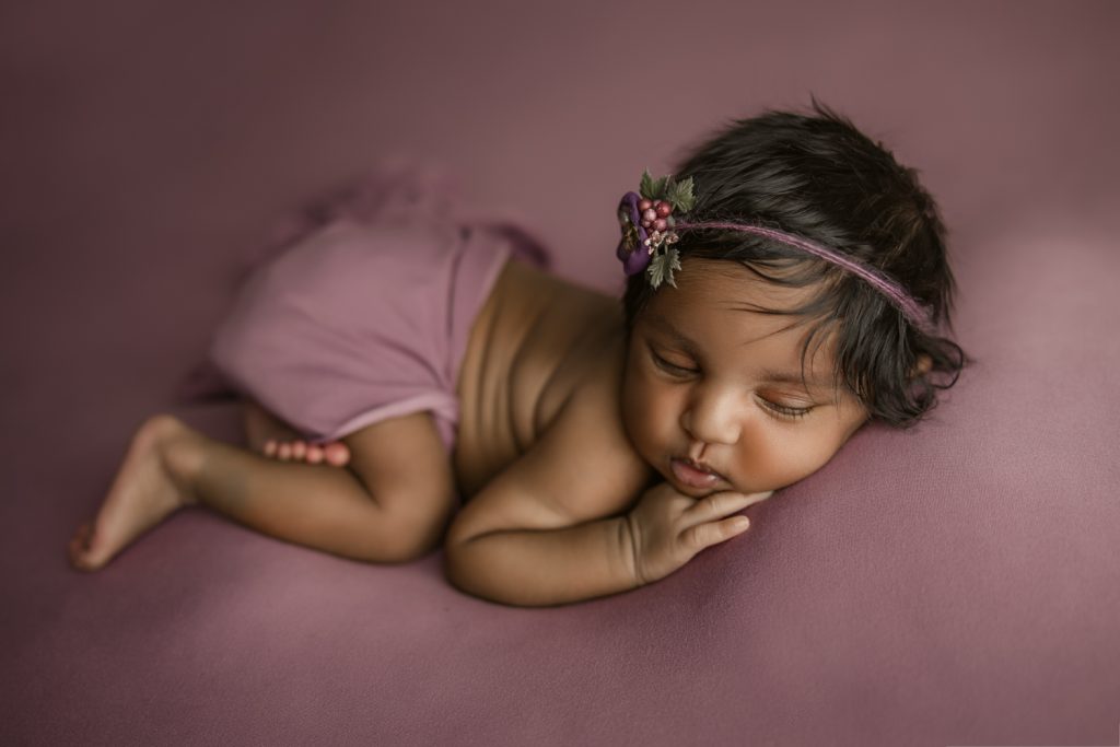 newborn baby girl sleeping on a dark berry color blanket during newborn photo session in Greensboro newborn photo studio