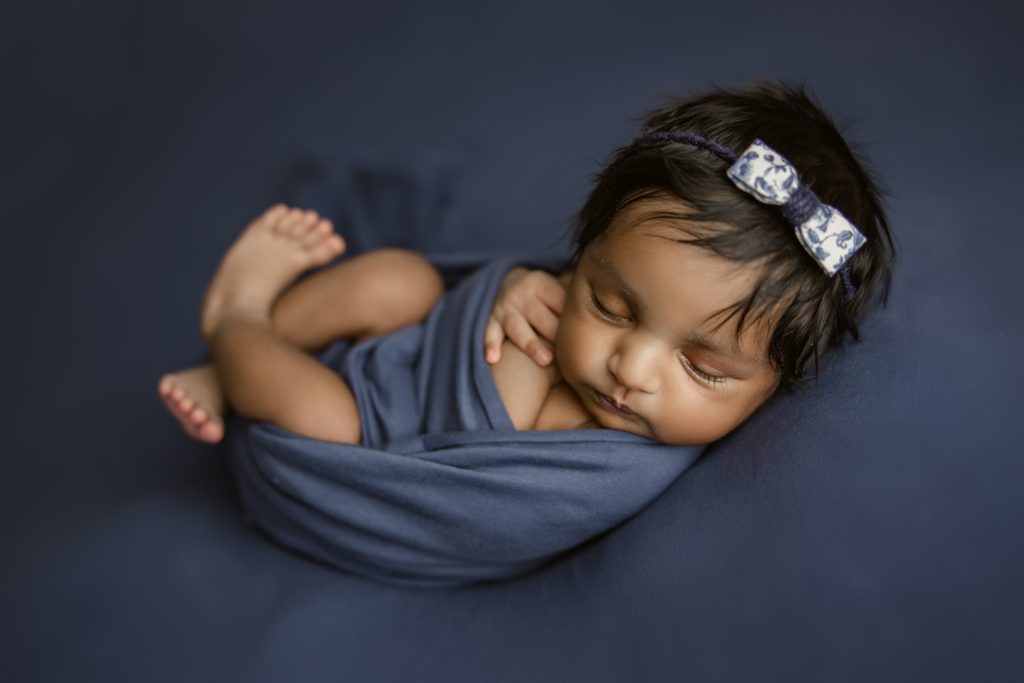 newborn baby girl on dark blue blanket during newborn photo session greensboro
