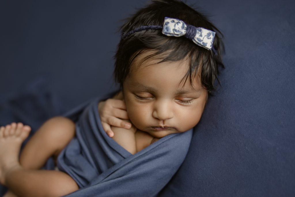 newborn baby girl on dark blue blanket during newborn photo session greensboro