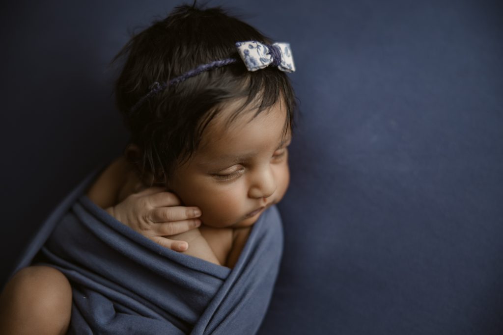 newborn baby girl on dark blue blanket during newborn photo session greensboro