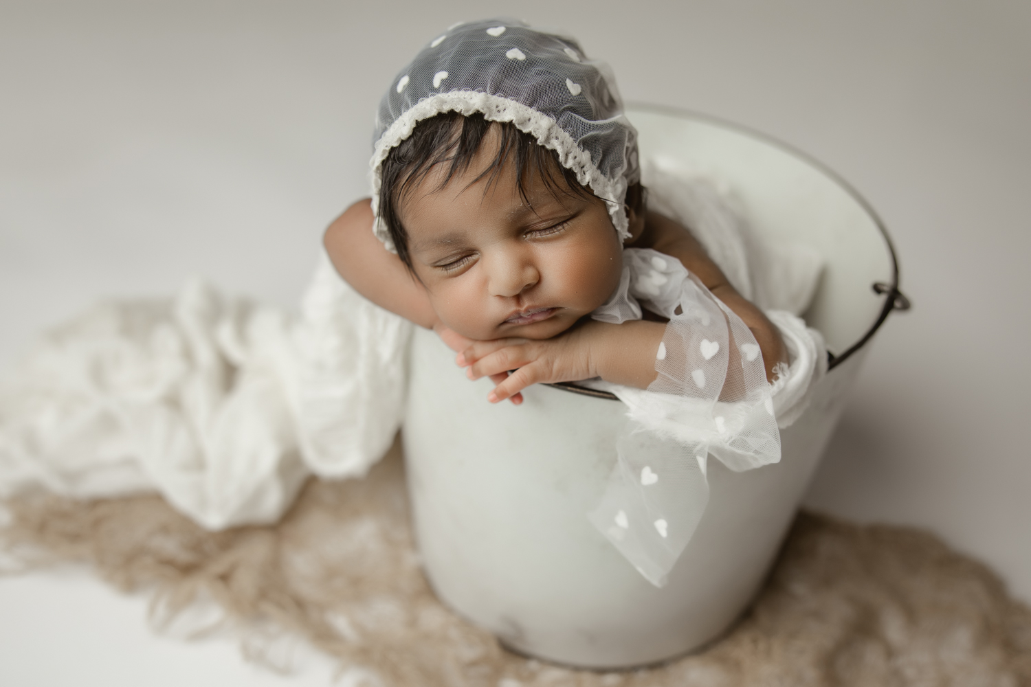 sleeping newborn baby girl sitting in a white bucket prop during newborn photo session Charlotte newborn photographer