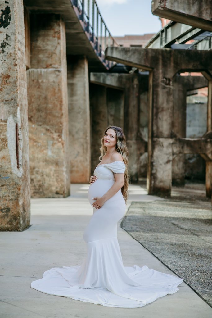 Maternity mother in white gown smiling at Innovation quarter, Bailey park downtown winston-salem North Carolina with Charlotte maternity photographer