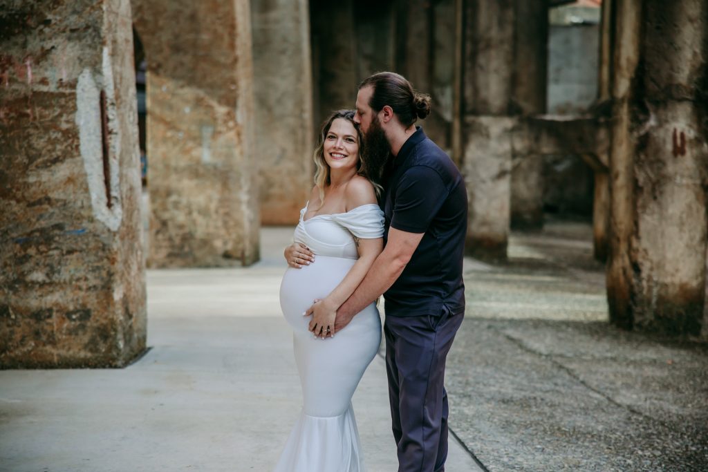 Maternity mother in white gown with husband in industrial background downtown winston-salem North Carolina Greensboro maternity photographer