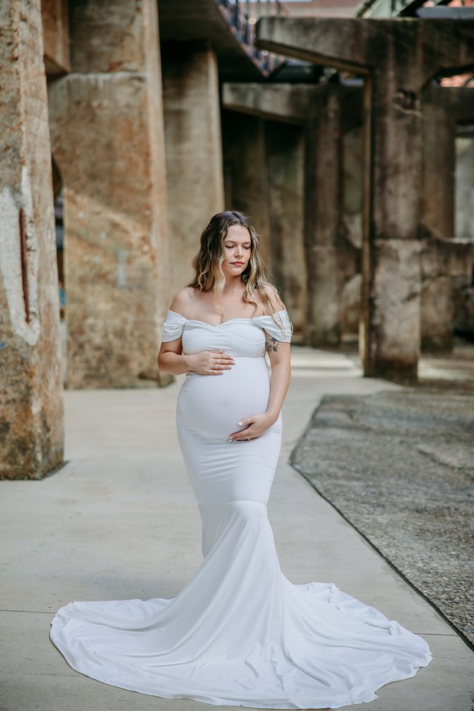Maternity mother in white gown smiling at Innovation quarter, Bailey park downtown winston-salem North Carolina with greensboro maternity photographer