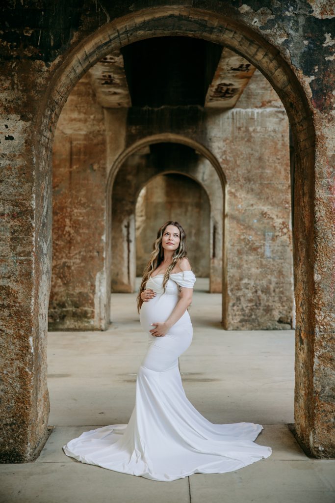 Maternity mother in white gown smiling at Innovation quarter, Bailey park downtown winston-salem North Carolina maternity photo session