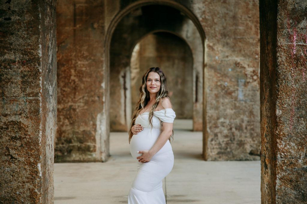 Maternity mother in white gown smiling at Innovation quarter, Bailey park downtown winston-salem North Carolina maternity photo session