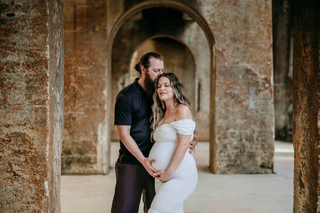 Maternity mother in white gown with husband in industrial background downtown winston-salem North Carolina Greensboro maternity photographer