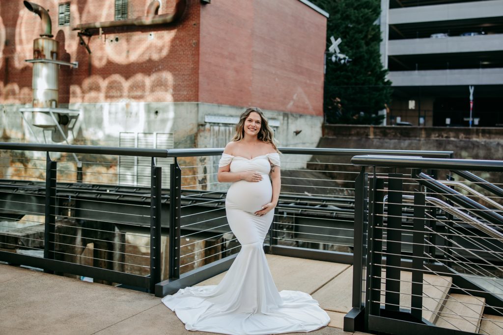 Maternity mother in white gown smiling at Innovation quarter, Bailey park downtown winston-salem North Carolina maternity photo session