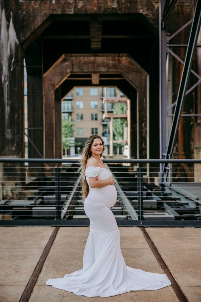 Maternity mother in white gown smiling at Innovation quarter, Bailey park downtown winston-salem North Carolina maternity photo session