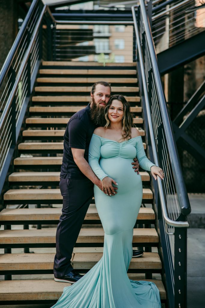 Elegant maternity mother in mint color standing on the stairs with husband at Innovation quarter, Bailey park downtown winston-salem North Carolina maternity photo session with greensboro maternity photographer