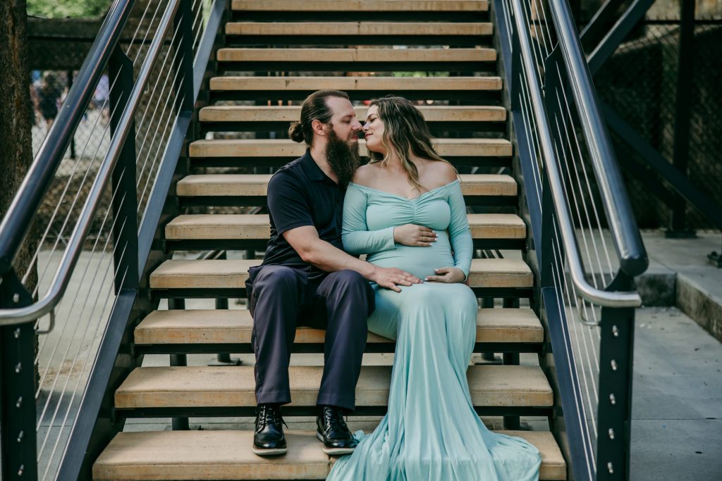 Elegant maternity mother in mint color sitting on the stairs with husband at Innovation quarter, Bailey park downtown winston-salem North Carolina maternity photo session with greensboro maternity photographer