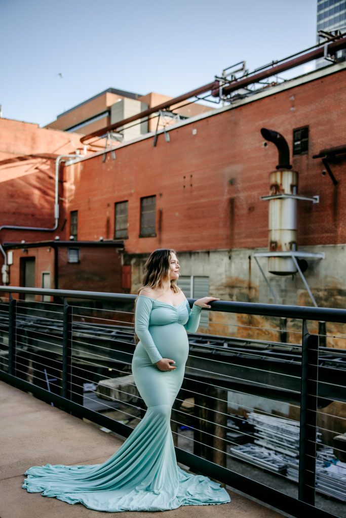 Maternity mother in mint color fitted gown looking away at Innovation quarter, Bailey park downtown winston-salem North Carolina maternity photo session