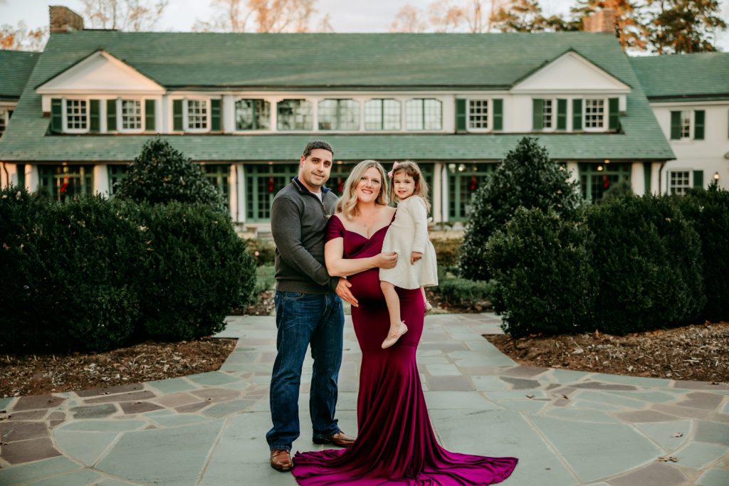 family with young toddler girl standing in front of Reynolda Museum during family photoshoot with Winston salem photographer