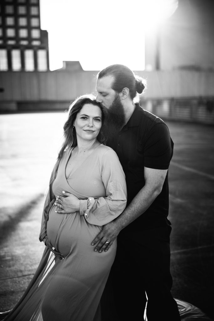 black and white maternity photo expectant mother with her husband at the rooftop parking lot in downtown Winston Salem with greensboro maternity photographer