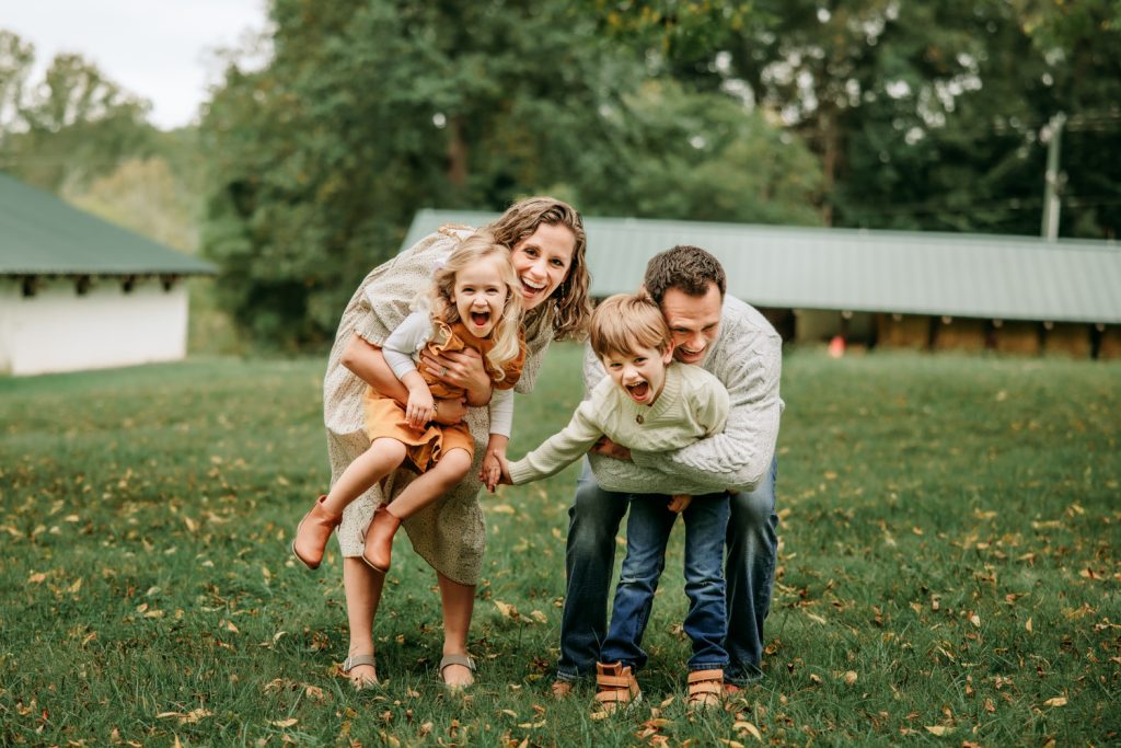 mom dad hugging kids from back laughing during Tanglewood park family photo session