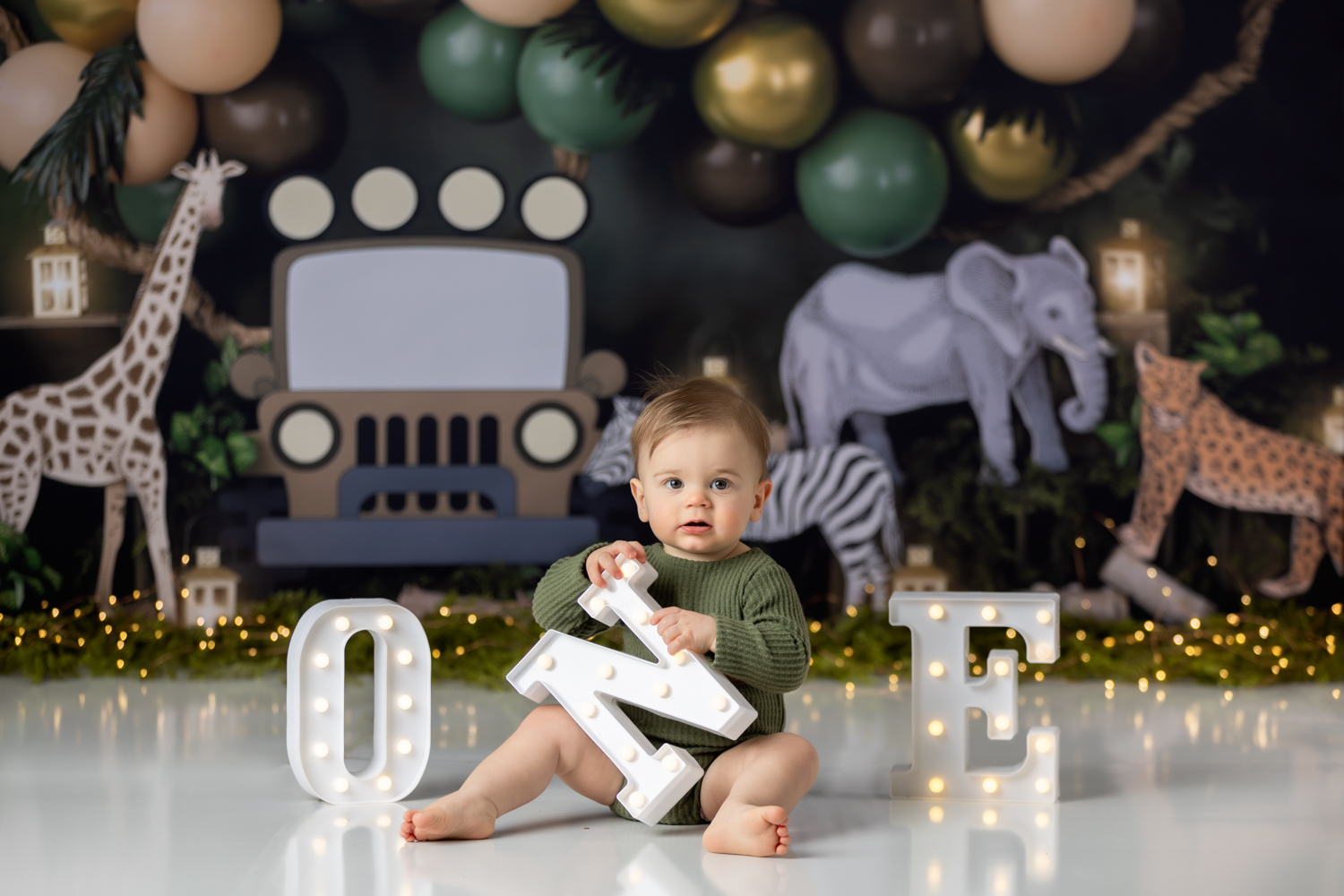 baby boy holding letter N while sittig between letter O and letter E during his first birthday photo session with greensboro baby photographer