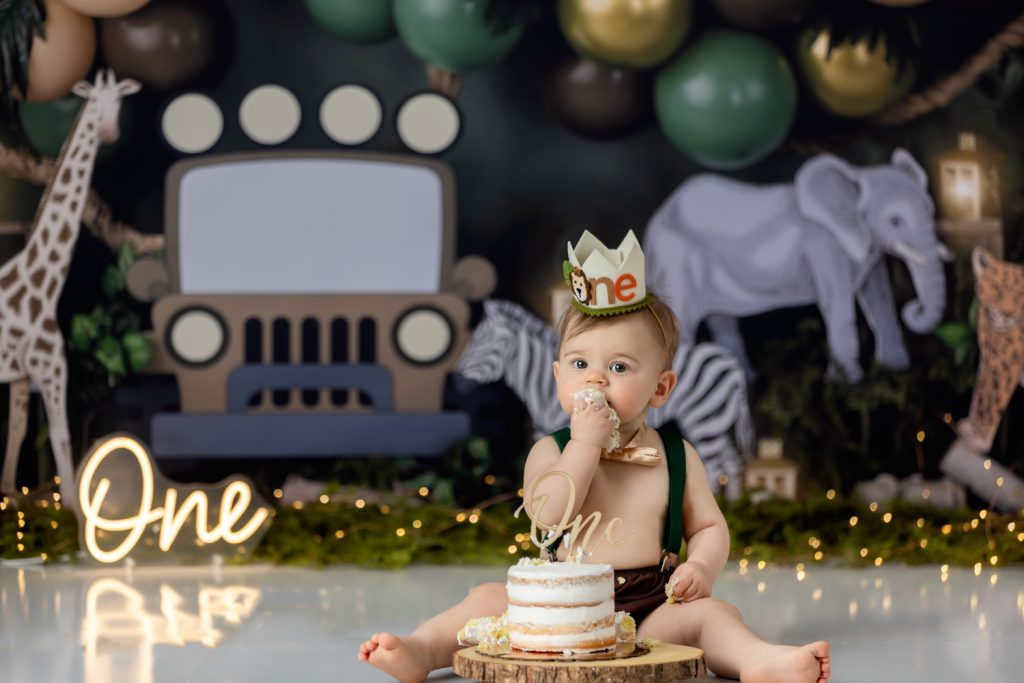 baby boy eating his birthday during wild one themed cake smash photo session with greensboro baby photographer