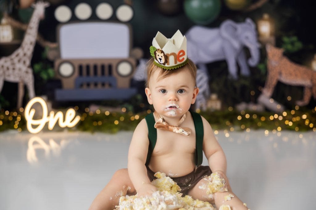 baby boy eating his birthday cake during wild one themed cake smash photo session with greensboro baby photographer