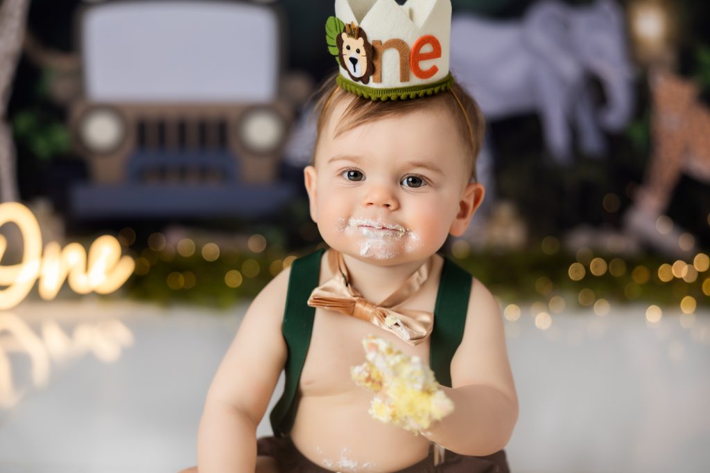 baby boy eating his birthday during wild one themed cake smash photo session with greensboro baby photographer