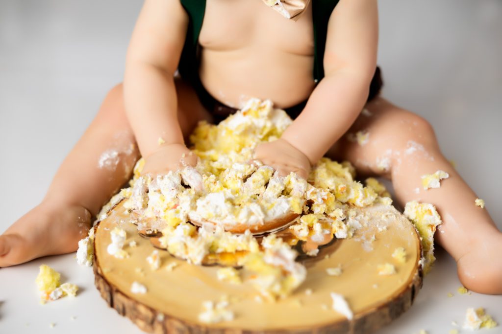 a close look of the smashed birthday cake by baby boy during wild one themed cake smash photo session with greensboro baby photographer