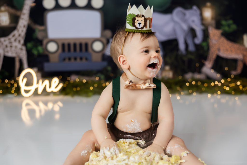 baby boy eating his birthday cake during wild one themed cake smash photo session with greensboro baby photographer