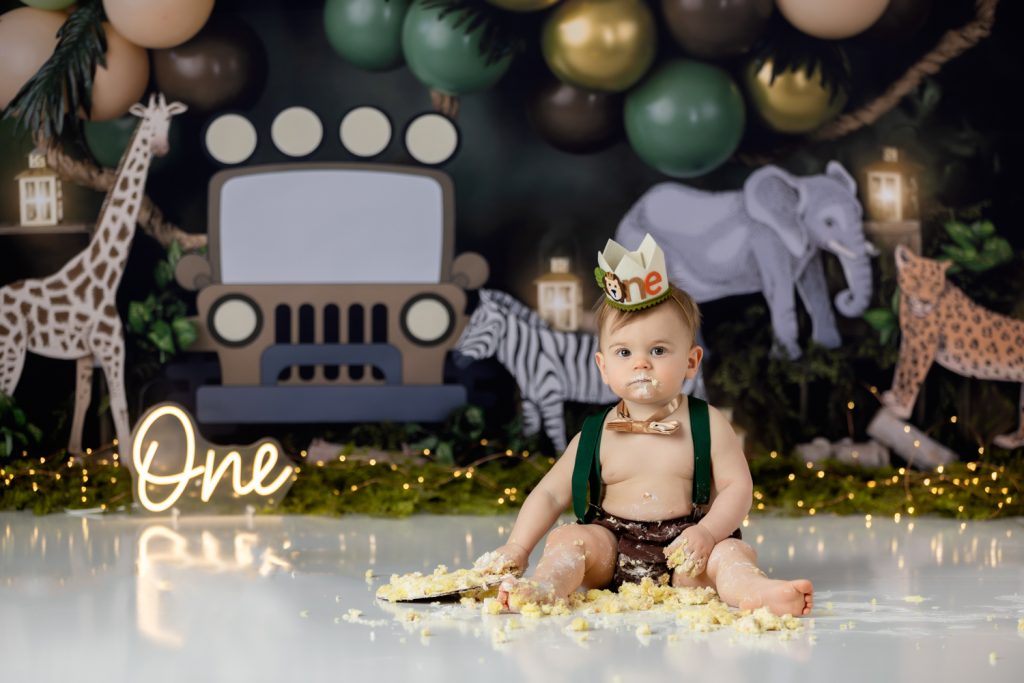 baby boy eating his birthday during wild one themed cake smash photo session with greensboro baby photographer