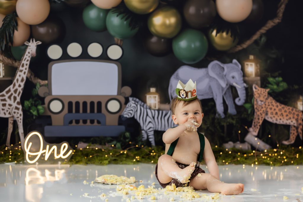 baby boy eating his birthday cake during wild one themed cake smash photo session with greensboro baby photographer