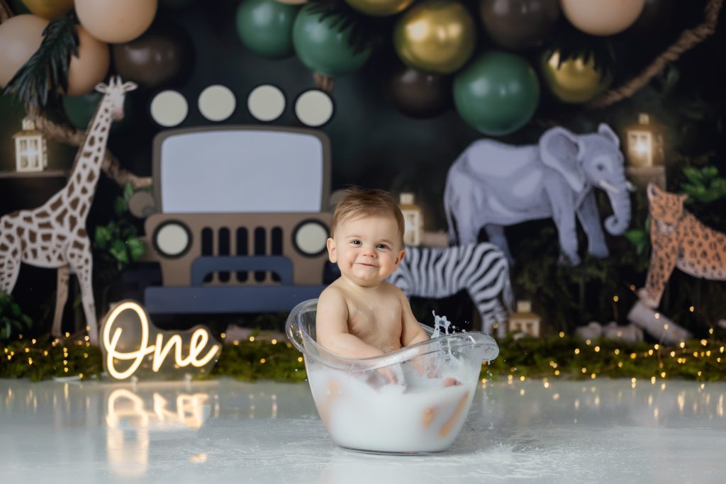 baby boy in milk bath during first birthday cake smash photoshoot with greensboro baby photographer