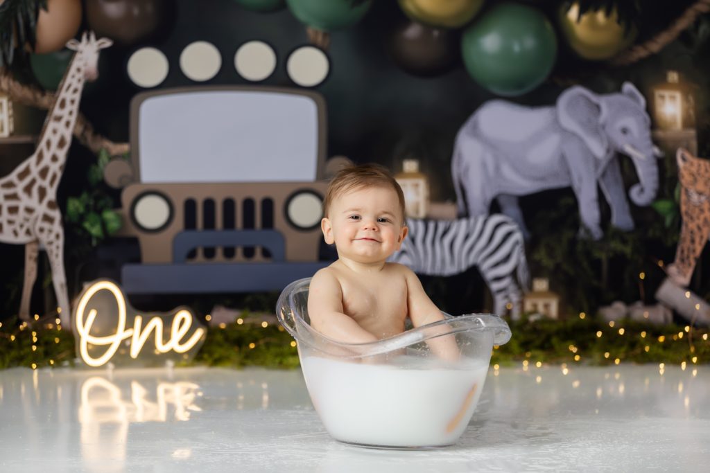 baby boy in milk bath during first birthday cake smash photoshoot with greensboro baby photographer