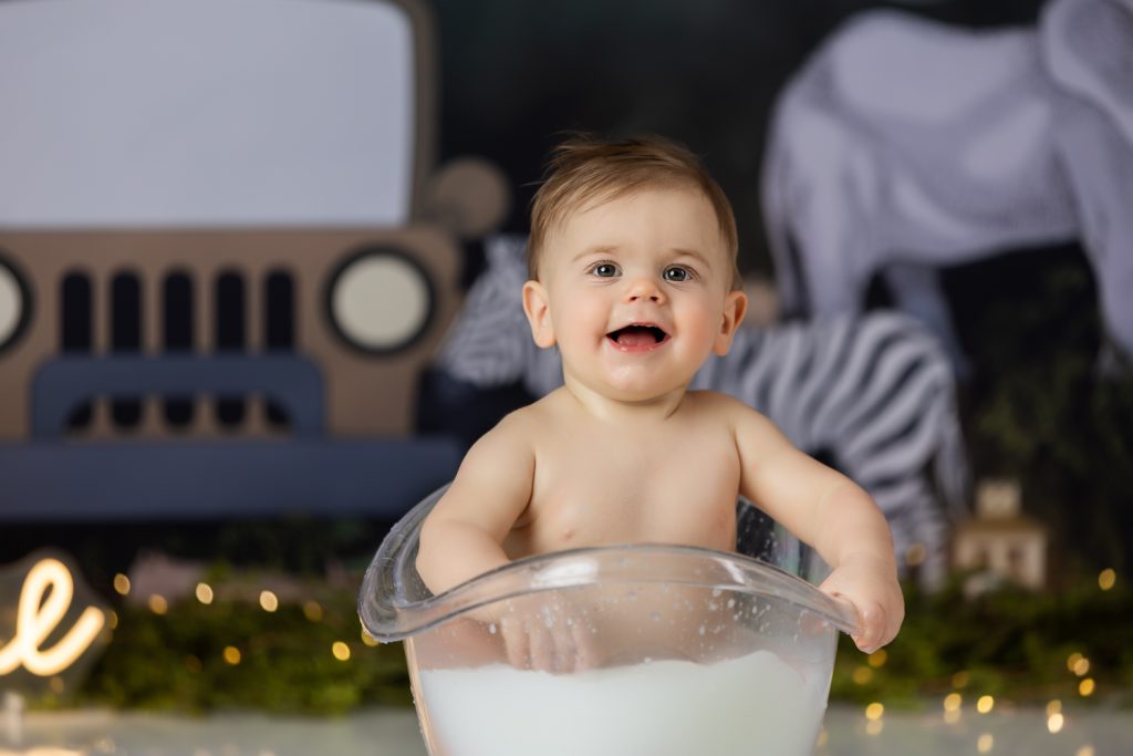 baby boy in milk bath during first birthday cake smash photoshoot with greensboro baby photographer