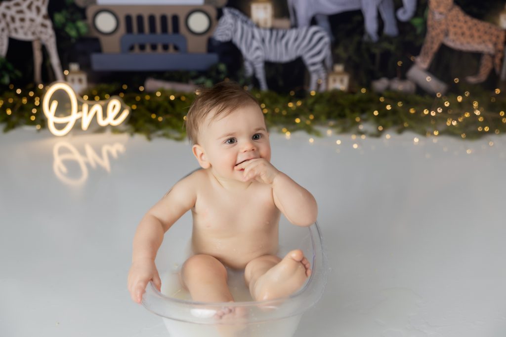 baby boy in milk bath during first birthday cake smash photoshoot with greensboro baby photographer