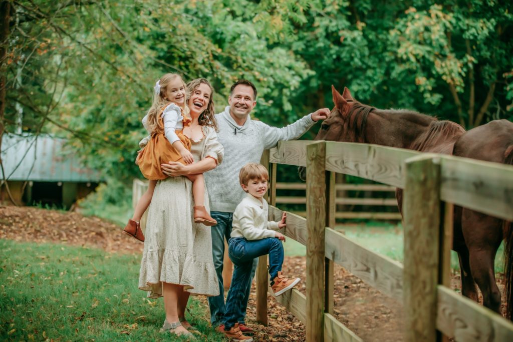family of 4 next to the horse smiling during Tanglewood park family photo session