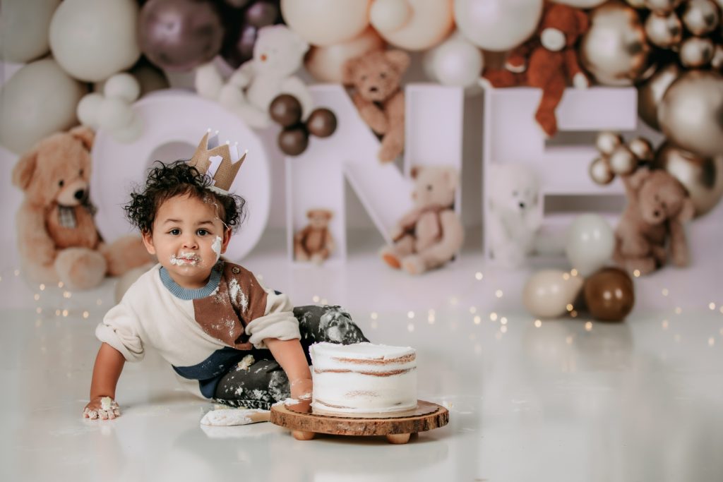 baby boy with icing in the face during cake smash photo session in Winston-salem baby photograohy studio