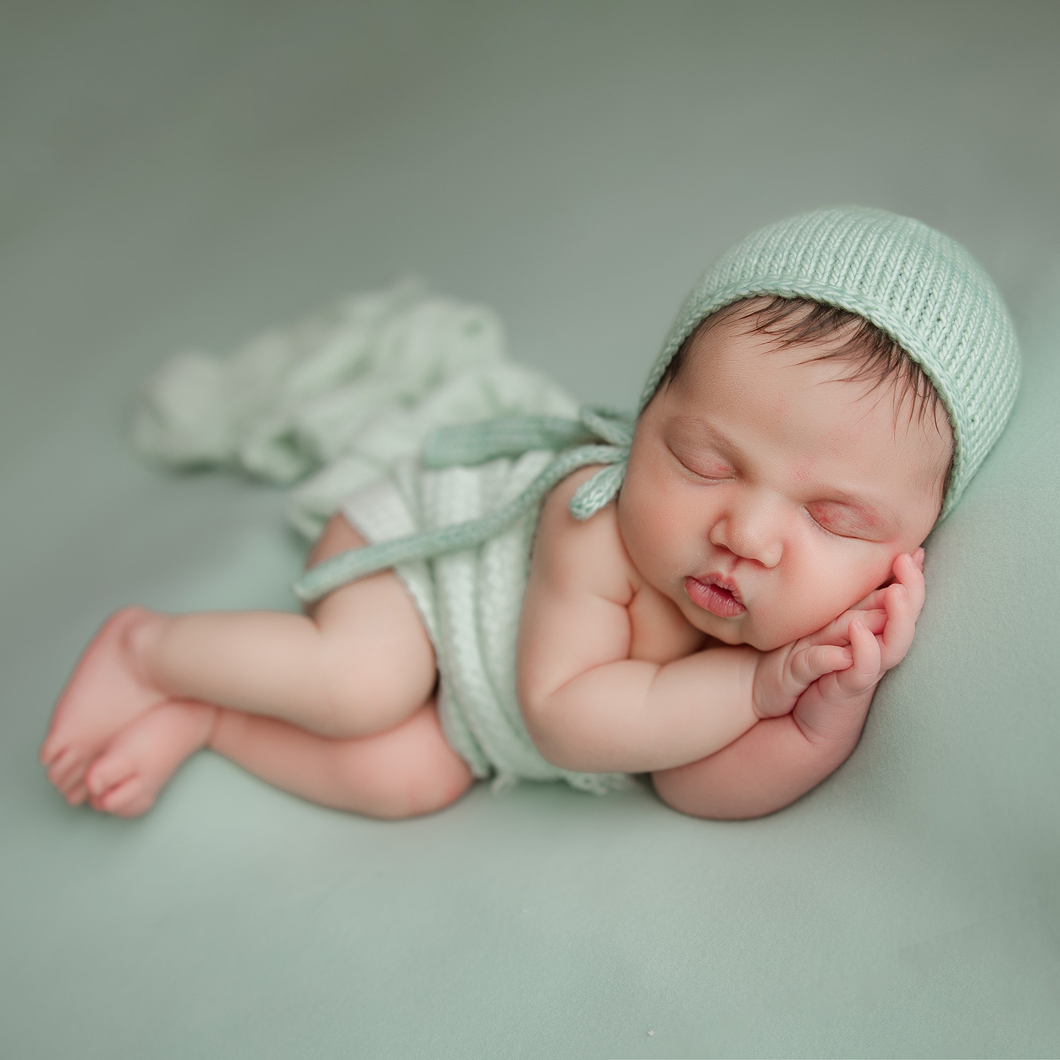 sleeping-newborn-baby-girl-in-mint-background-wearing-a-mint-bonnet-during-greensboro-newborn-photo-session
