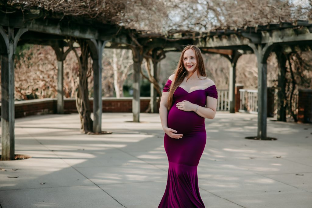 maternity mother in elegant fitted dress during maternity photo session in tanglewood arboretum Winston Salem NC