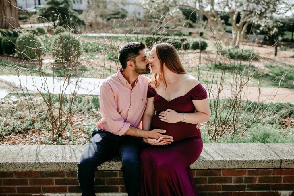 maternity mother in elegant fitted dress with her husband during maternity photo session in tanglewood arboretum Winston Salem NC