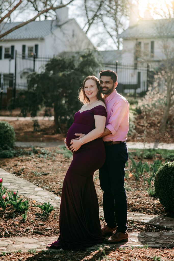 maternity mother in elegant fitted dress with her husband during maternity photo session in tanglewood arboretum Winston Salem NC