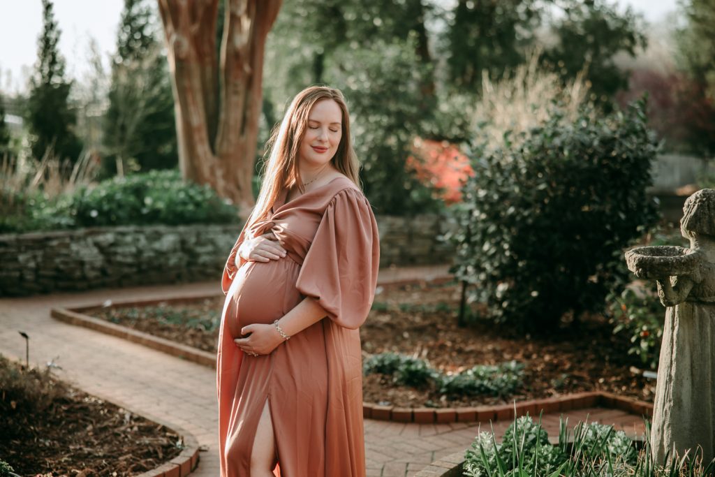 beautiful-expectant-mother-in-flowy-dusty-pink-gown-in-tanglewood-park-garden-during-maternity-photo-session-with-winston-salem-motherhood-photographer