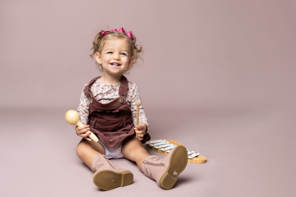 cute baby girl in clay pink corduroy dress during classic baby portrait with greensboro baby photographer